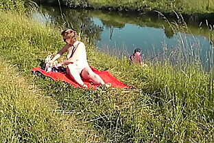 MILF sexy Frina on river bank undressed and sunbathes naked. Random man fisherman watching for her, and in the end decided to join naked woman. Wild beach. Nudist beach. Public nudity. Public exposure. Naked in public poster